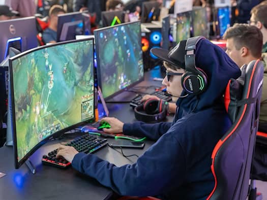Esports-Spieler mit Headset und Gaming-Maus an einem Curved-Monitor während eines Turniers.