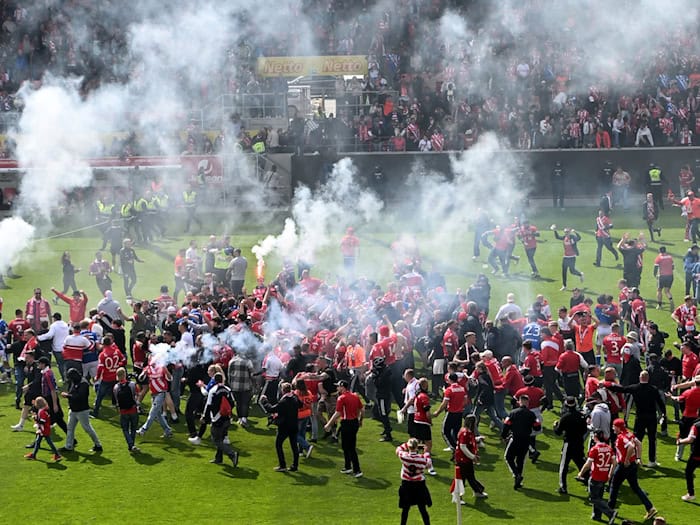 Aufstiegsfeier mit Pyrotechnik: Fans des FC Energie Cottbus auf dem Spielfeld in Regensburg. / Foto: Jens Niering/dpa