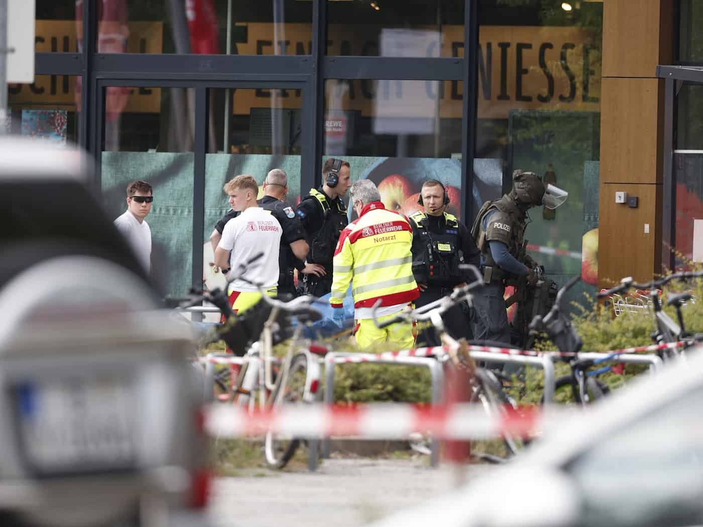 Einsatzkräfte stehen vor einem Supermarkt neben einer verletzten Person auf einer Trage / Foto: Carsten Koall/dpa
