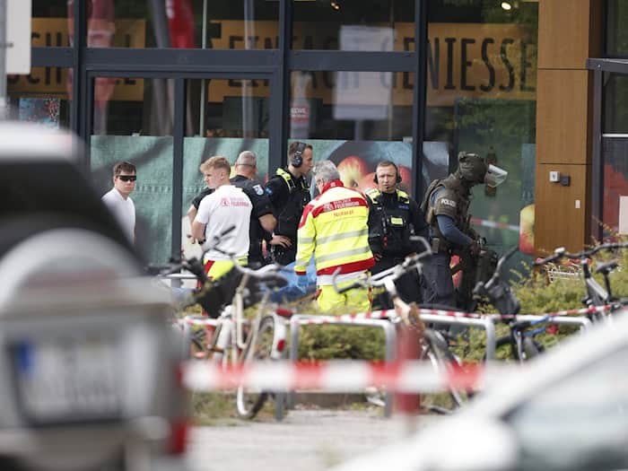 Einsatzkräfte stehen vor einem Supermarkt neben einer verletzten Person auf einer Trage / Foto: Carsten Koall/dpa