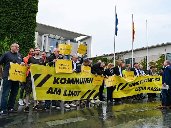 Vertreter mehrerer Städte und Kommunen demonstrieren mit Schildern und Bannern für finanzielle Unterstützung in Berlin. / Foto: Jens Kalaene/dpa
