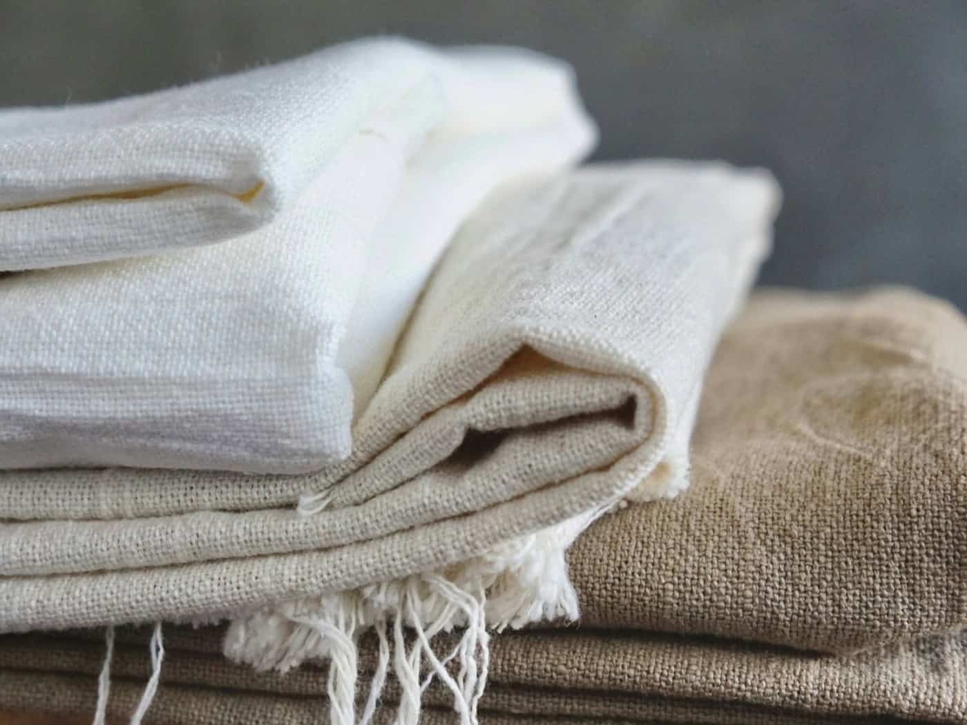 Stapel aus natürlichem Leinenstoff in verschiedenen Beige- und Weißtönen