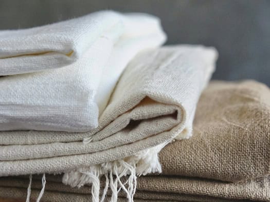 Stapel aus natürlichem Leinenstoff in verschiedenen Beige- und Weißtönen