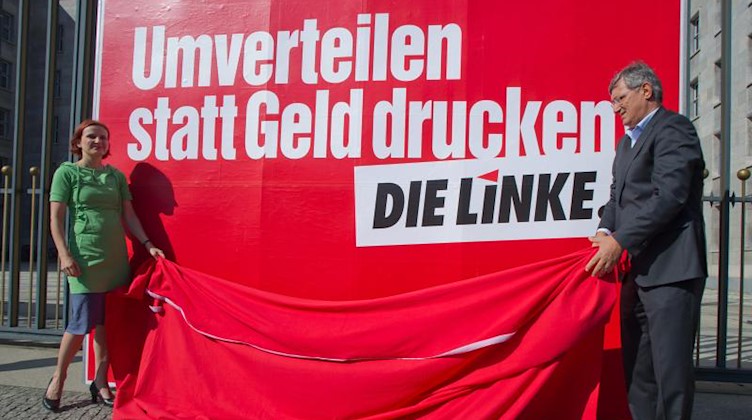 Die Vorsitzenden von der Partei "Die Linke", Katja Kipping (l) und Bernd Riexinger, präsentieren 2012 ein Großflächenplakat. Foto: Tim Brakemeier/dpa/Archivbild