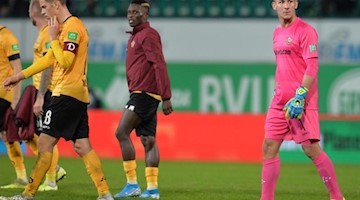 Torwart Kevin Broll (r) von Dresden geht nach dem Spiel über den Rasen. Foto: Timm Schamberger/dpa