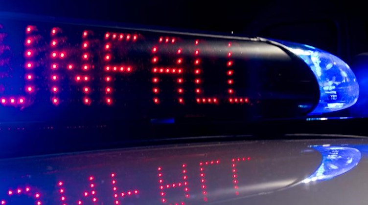 Das Blaulicht auf einem Polizeiauto leuchtet, während auf dem Display der Hinweis «Unfall» zu lesen ist. Foto: Monika Skolimowska/zb/dpa/Archivbild