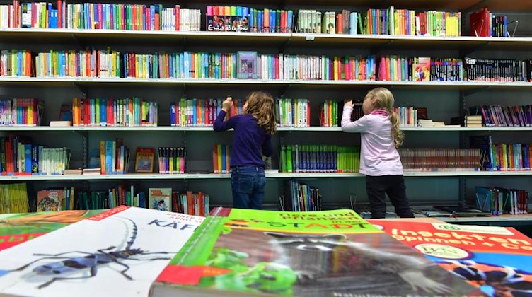 Zwei Kinder stöbern in einer Bücherei nach Büchern. Foto: Martin Schutt/dpa-Zentralbild/dpa/Archivbild