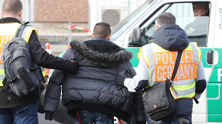 Polizisten begleiten einen straffällig gewordenen Asylbewerber zu seinem Abflug. Foto: Sebastian Willnow/dpa-Zentralbild/dpa/Archivbild