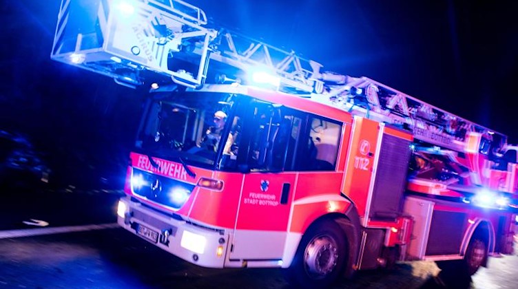 Ein Drehleiterwagen der Feuerwehr fährt mit Blaulicht an einer Unfallstelle vorbei. Foto: Marcel Kusch/dpa