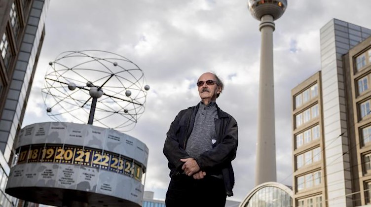 Michael Masur steht am Alexanderplatz vor der Weltzeituhr und dem Berliner Fernsehturm. Foto: Christoph Soeder/dpa