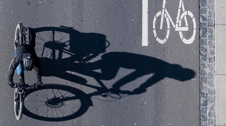 Eine Fahrradfahrerin fährt über eine Straße mit einer Markierung für Fahrräder. Foto: Julian Stratenschulte/dpa