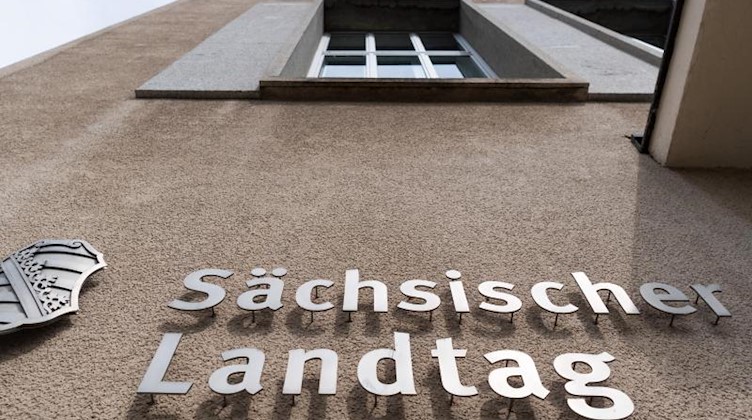Ein Sachsen-Wappen und der Schriftzug Sächsischer Landtag sind an der Fassade des Landtages angebracht. Foto: Robert Michael/zb/dpa