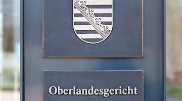 Ein Aufsteller mit dem Wappen von Sachsen und der Aufschrift «Oberlandesgericht» steht am Eingang des Gerichtsgebäudes. Foto: Robert Michael/zb/dpa