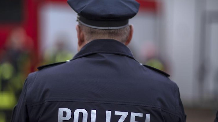 Polizisten stehen vor einem Polizeifahrzeug. Foto: Jens Büttner/zb/dpa/Archiv