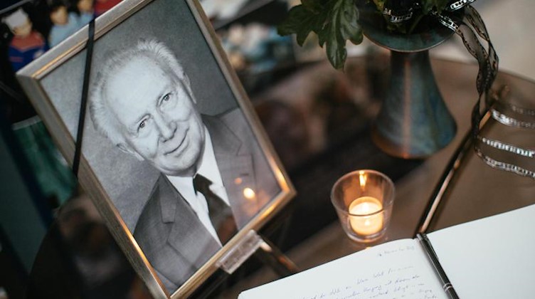 Ein Kondolenzbuch, eine Kerze, Blumen und ein Portrait bei der Gedenkfeier für Sigmund Jähn. Foto: Oliver Killig/dpa-Zentralbild/dpa