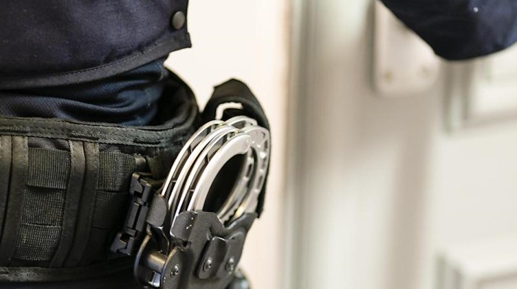 Handschellen sind an einem Gürtel eines Polizisten befestigt. Foto: Frank Molter/dpa
