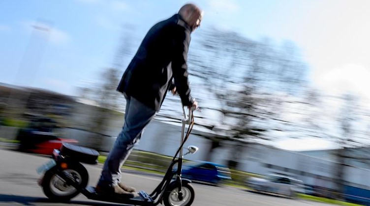 Ein Mann fährt mit einem E-Scooter. Foto: Christophe Gateau/dpa