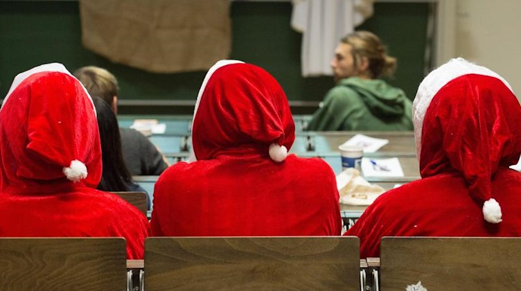 Als Weihnachtsmann verkleidete Studenten sitzen in einem Hörsaal. Foto: Sebastian Kahnert/zb/dpa