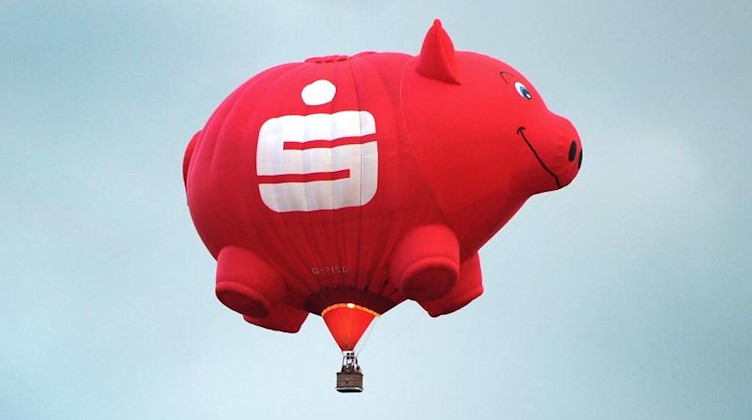Ein Heißluftballon in der Form eines Sparschweines mit Sparkassen-Logo ist am Himmel zu sehen. Foto: Daniel Naupold/dpa/Archivbild