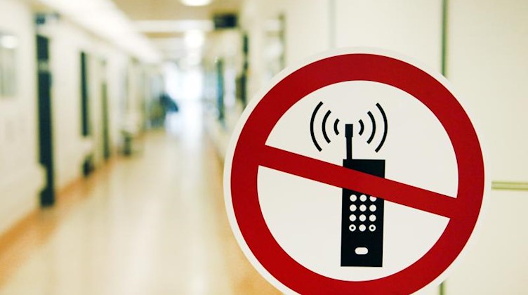 Ein Handy-Verbotsschild klebt in Hamburg im Albertinen-Krankenhaus an einer Glastür. Foto: Sebastian Widmann/dpa