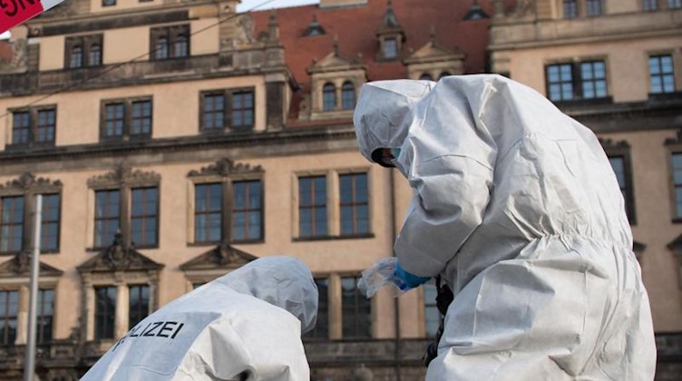 Zwei Mitarbeiter der Spurensicherung stehen vor dem Residenzschloss hinter einem Absperrband. Foto: Sebastian Kahnert/dpa-Zentralbild/dpa