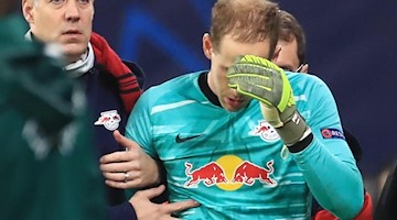 Leipzigs Torwart Peter Gulacsi (r) verlässt nach einem Zusammenstoss mit Benficas Vinicius das Spielfeld. Foto: Jan Woitas/dpa