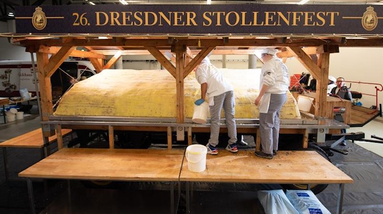 Bäcker der Schutzgemeinschaft Dresdner Stollen streichen Butter und Zucker auf den Riesenstollen. Foto: Sebastian Kahnert/dpa-Zentralbild/dpa