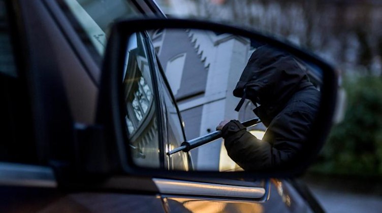 Ein Mann versucht eine Autotür mit einer Metallstange aufzubrechen. Foto: Axel Heimken/dpa
