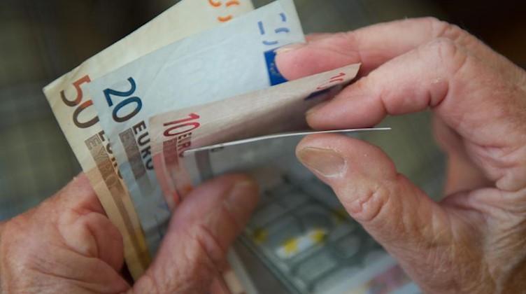 Eine ältere Frau zählt Geld. Foto: Marijan Murat/dpa/Archivbild