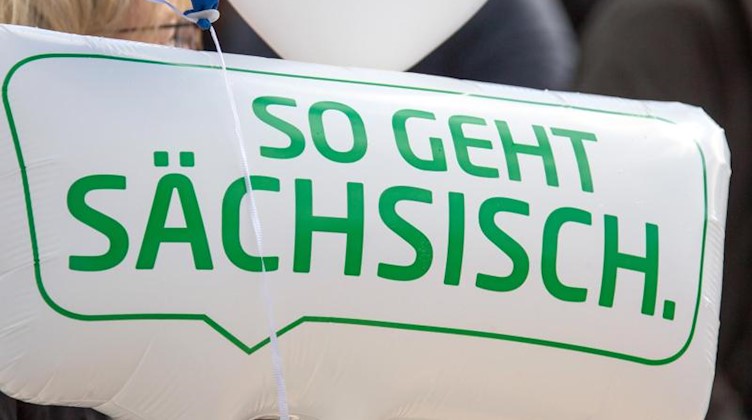Ein Luftballon in Sprechblasenform mit der Aufschrift «So geht Sächsisch» ist zu sehen. Foto: Jens Büttner/zb/dpa