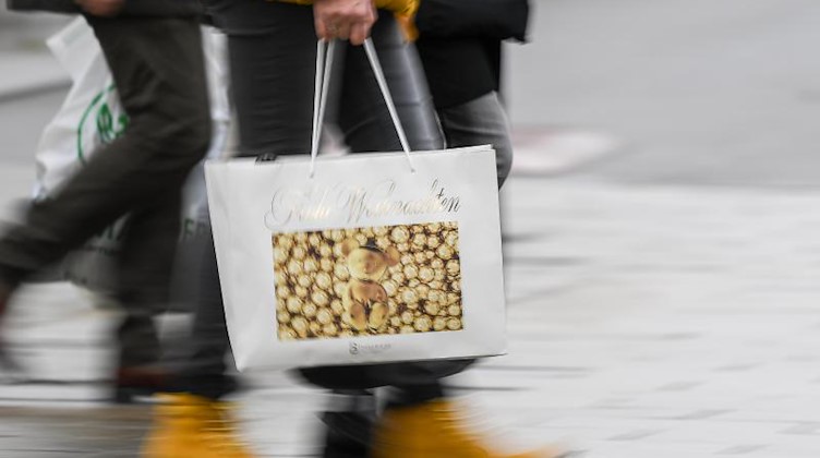 Eine Frau geht mit einer Einkaufstasche in weihnachtlicher Optik durch die Innenstadt. Foto: Sebastian Gollnow/dpa/Archivbild