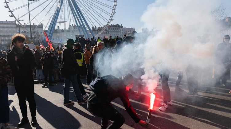 Ein Demonstrant zündet Pyrotechnik während einer Demonstration am Platz Bellecour. Foto: Robert Michael/dpa-Zentralbild/dpa
