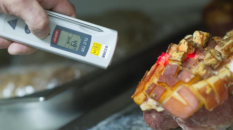 Ein Lebensmittelkontrolleur überprüft bei einer Betriebskontrolle die Temperatur einer Fleischware. Foto: Uwe Anspach/dpa/Archivbild