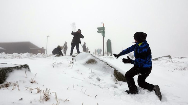 Erwachsene und Kinder liefern sich auf dem Gipfel des Brocken eine Schneeballschlacht. Foto: Matthias Strauss/dpa/Archiv