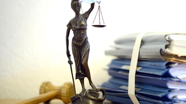 Eine modellhafte Nachbildung der Justitia steht neben Akten und einem Richterhammer auf einem Tisch. Foto: Volker Hartmann/dpa/Archivbild