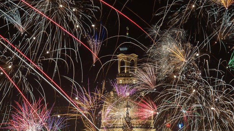 Feuerwerk explodiert an Silvester über der histoischen Altstadtkulisse mit der Frauenkirche. Foto: Robert Michael/dpa-Zentralbild/dpa