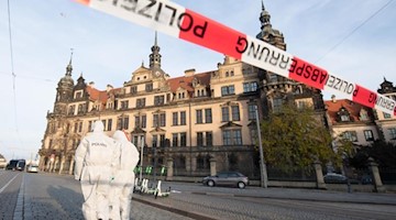 Zwei Mitarbeiter der Spurensicherung stehen vor dem Residenzschloss mit dem Grünen Gewölbe hinter einem Absperrband. Foto: Sebastian Kahnert/zb/dpa/Archiv