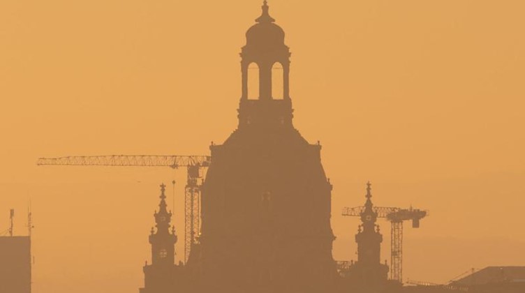 Die Silouhette der Frauenkirche ist bei Sonnenaufgang zu sehen. Foto: Sebastian Kahnert/dpa-Zentralbild/dpa
