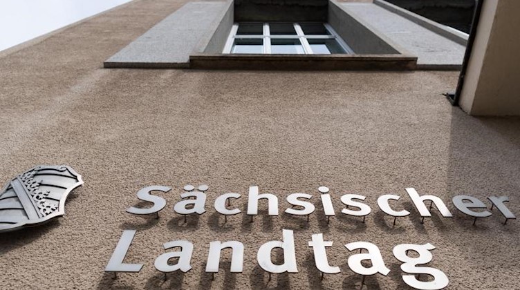 Ein Sachsen-Wappen und der Schriftzug «Sächsischer Landtag» sind an der Fassade des Landtages angebracht. Foto: Robert Michael/zb/dpa/Archivbild
