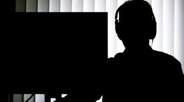 Ein Beamter sitzt für eine Telefonüberwachung vor einem Computer. Foto: Christian Charisius/dpa