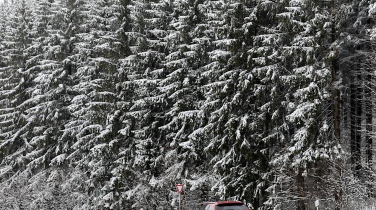 Ein Auto fährt auf einer Landstraße durch den verschneiten Wald bei Einsiedel. Foto: Jan Woitas/dpa-Zentralbild/dpa