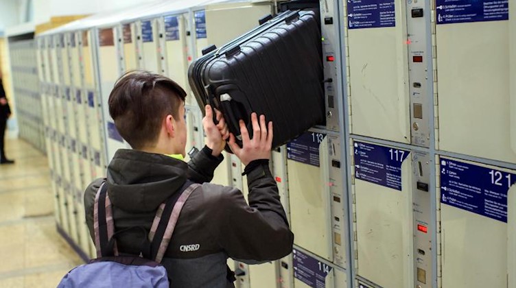 Ein Reisender verstaut seinen Rollkoffer in einem Schließfach. Foto: Gregor Fischer/dpa/Archivbild