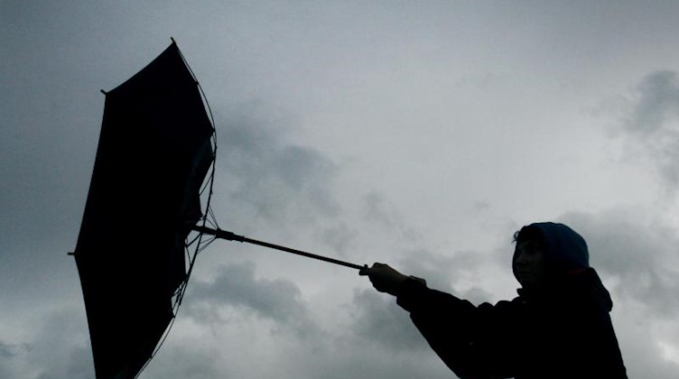 Ein Regenschirm eines Spaziergängers wird von einer Windböe erfasst. Foto: picture alliance / Karl-Josef Hildenbrand/dpa/Archivbild