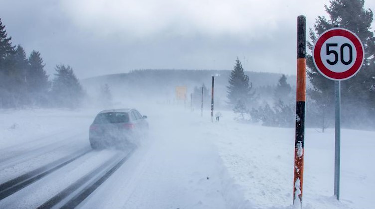 Autos fahren durch vom Wind aufgewirbelte Schneewolken auf der Zufahrtsstraße zum Fichtelberg. Foto: Jens Büttner/dpa-Zentralbild/dpa/Archivbild
