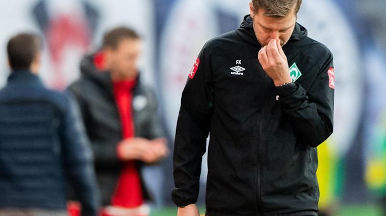 Bremens Trainer Florian Kohfeldt fasst sich an die Nase. Foto: Robert Michael/dpa
