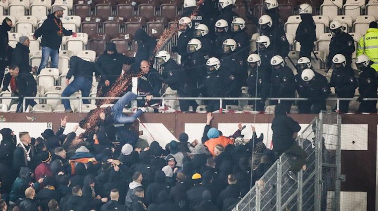 Polizeikräfte drängen randalierende Fans von Dynamo Dresden zurück in den Gästeblock. Foto: Christian Charisius/dpa