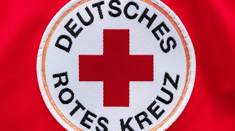 Das Logo des Deutschen Roten Kreuzes ist auf rotem Hintergund zu sehen. Foto: Markus Scholz/dpa/Archivbild