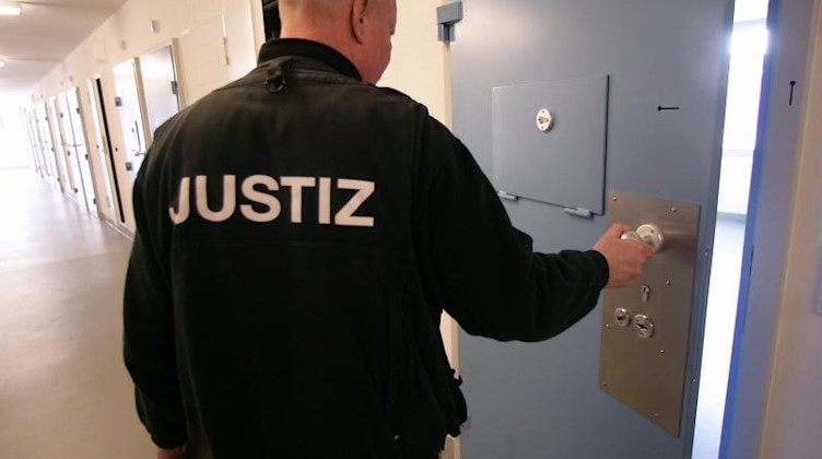Ein Justizvollzugsbeamter öffnet in einer Justizvollzugsanstalt die Tür eines Haftraumes. Foto: Jens Wolf/dpa-Zentralbild/dpa/Archiv