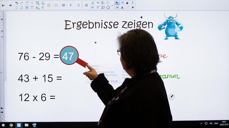 Eine Lehrerin steht vor einen digitalen Schultafel. Foto: Julian Stratenschulte/dpa