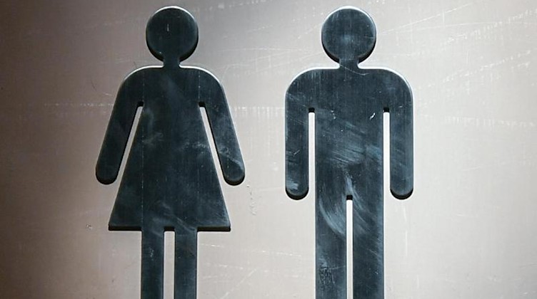 Piktogramme für eine Frau und ein Mann sind an einer Toiletten-Tür angebracht. Foto: Jens Kalaene/dpa-Zentralbild/dpa